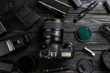 Siyah ahşap masada profesyonel fotoğrafçı için ekipmanla düz kompozisyon.
