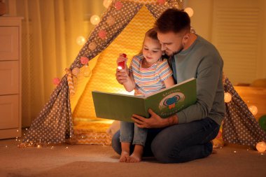 Evde el feneri okuyan baba ve kızı.