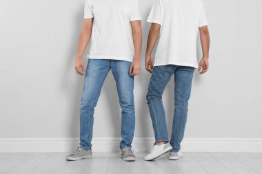 Işık duvarının yanında şık kotlu genç adamlar, yakın plan.