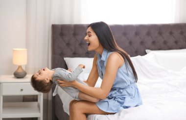 Genç dadı yatak odasında küçük şirin bir bebekle oynuyor.