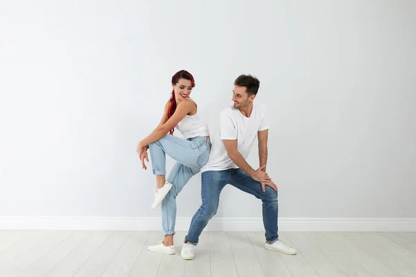 Hermosa pareja joven bailando cerca de pared de luz — Foto de Stock