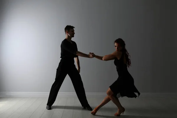Красивая молодая пара танцует у светлой стены — стоковое фото