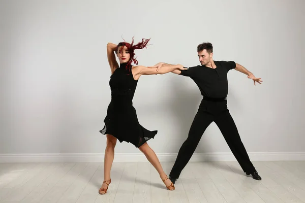 Hermosa pareja joven bailando cerca de pared de luz — Foto de Stock