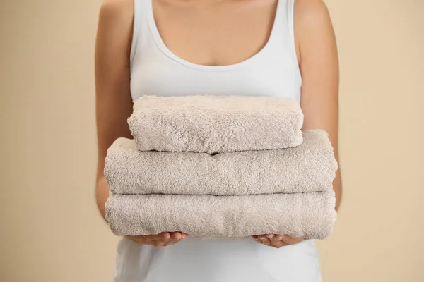 Γυναίκα Κρατώντας Καθαρές Πετσέτες Μπεζ Φόντο Closeup — Φωτογραφία Αρχείου