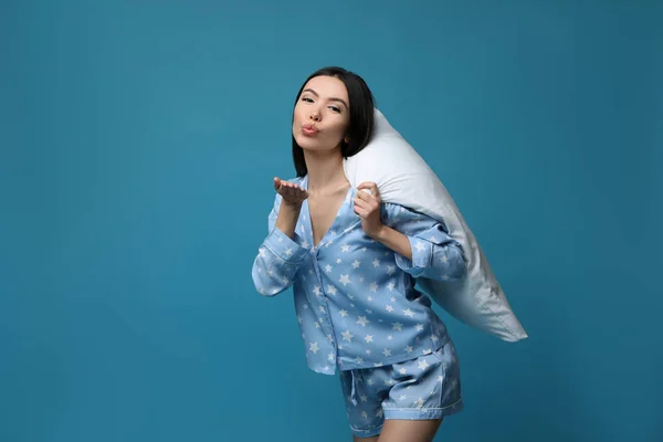 Bella donna asiatica con cuscino che soffia bacio sul backgroun blu — Foto Stock