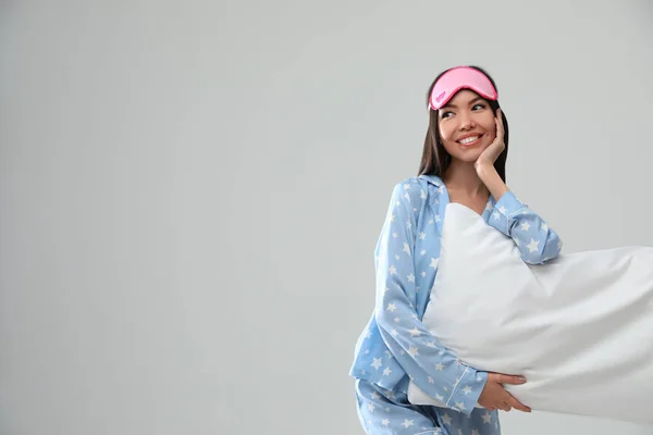 Schöne asiatische Frau mit Kissen auf hellgrauem Hintergrund, spac — Stockfoto