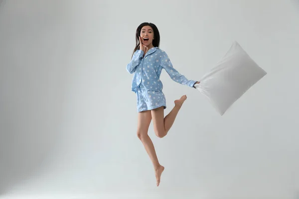 Vacker asiatisk kvinna med kudde hoppar på ljusgrå backgrou — Stockfoto