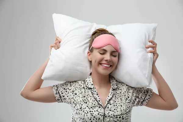 Hermosa mujer con almohada sobre fondo gris claro. Hora de dormir —  Fotos de Stock