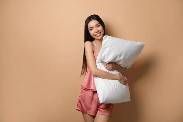 Schöne asiatische Frau mit Kissen auf beigem Hintergrund. Schlafenszeit — Stockfoto