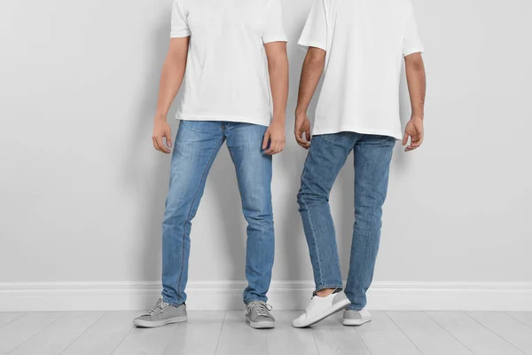 Junge Männer in stylischen Jeans nahe Lichtwand, Nahaufnahme — Stockfoto