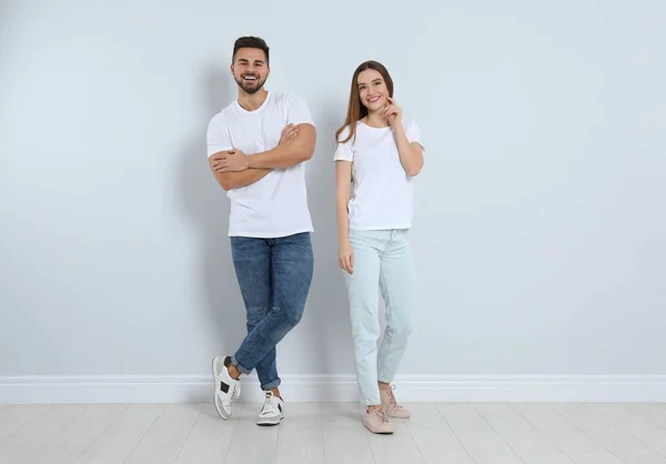 Ungt par i snygga jeans nära ljus vägg — Stockfoto