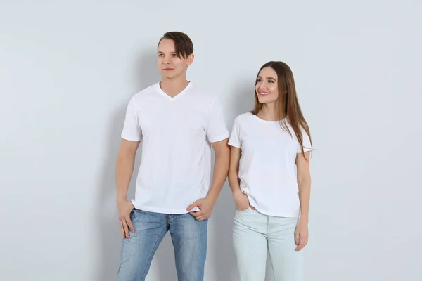 Jovem casal em jeans elegantes no fundo claro — Fotografia de Stock