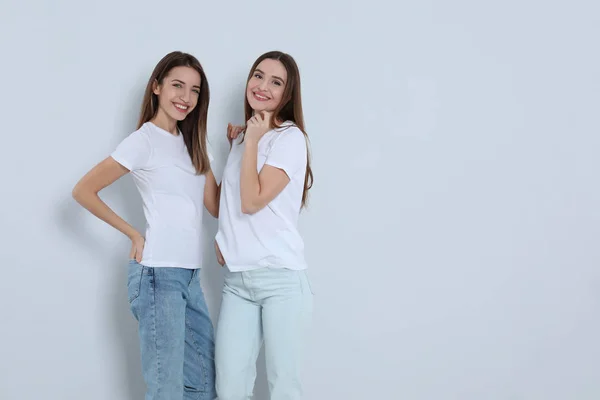 Jovens mulheres em jeans elegantes no fundo claro. Espaço para texto — Fotografia de Stock