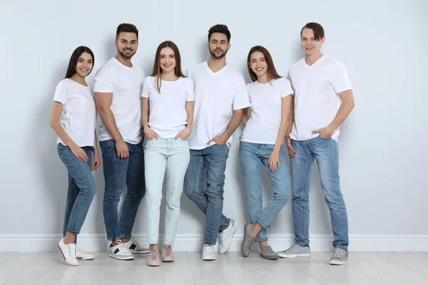 Група молодих людей в стильних джинсах біля світлої стіни — стокове фото