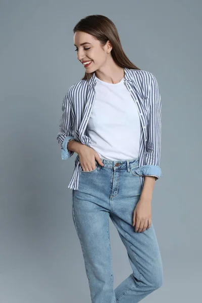 Mujer joven en jeans con estilo sobre fondo gris — Foto de Stock