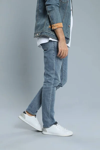 Giovane in jeans alla moda su sfondo grigio, primo piano — Foto Stock