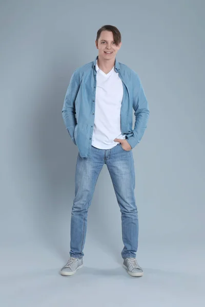 Hombre joven en jeans con estilo sobre fondo gris —  Fotos de Stock