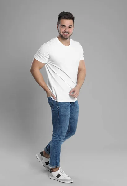 Ung man i snygga jeans på grå bakgrund — Stockfoto