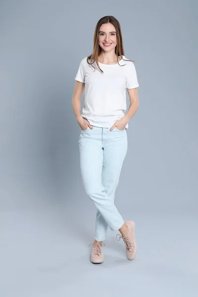 Молодая женщина в стильных джинсах на сером фоне — стоковое фото