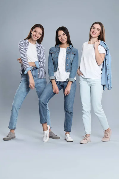 Grupo de mujeres jóvenes en jeans con estilo sobre fondo gris — Foto de Stock