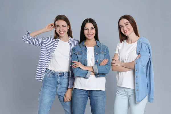 Група молодих жінок у стильних джинсах на сірому фоні — стокове фото