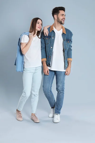 Jovem casal em jeans elegantes no fundo cinza — Fotografia de Stock