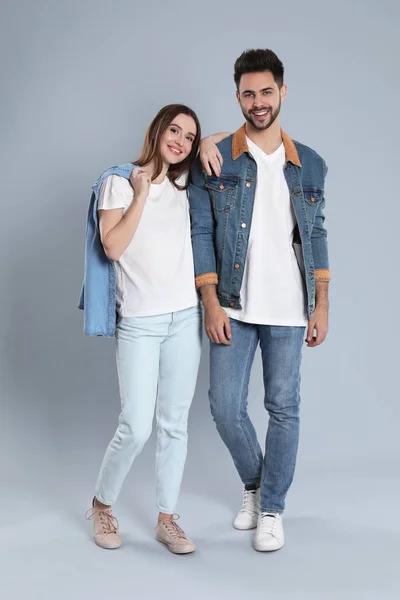 Pareja joven en jeans con estilo sobre fondo gris — Foto de Stock