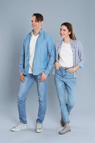 Jong stel in stijlvolle jeans op grijze achtergrond — Stockfoto