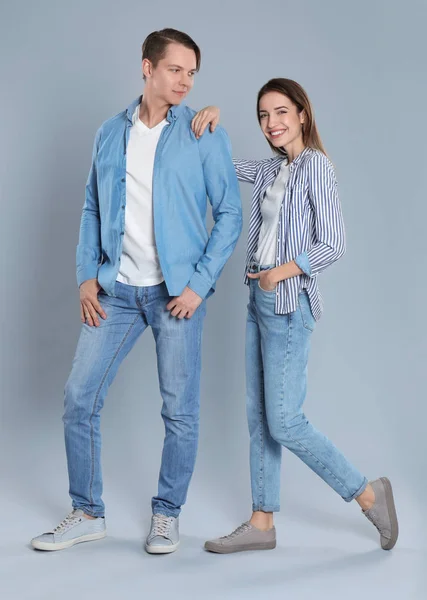 Pareja joven en jeans con estilo sobre fondo gris — Foto de Stock