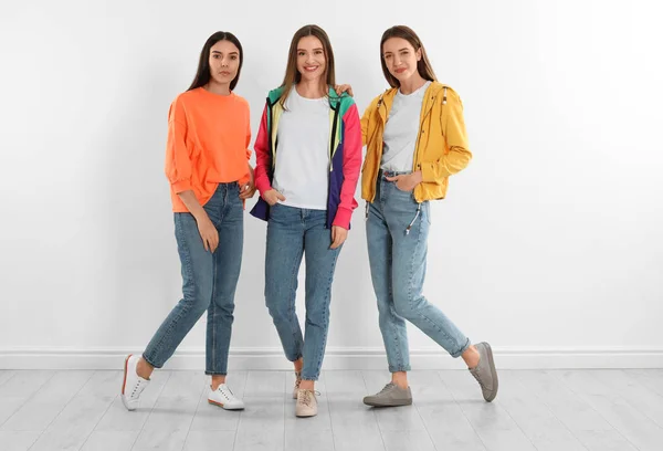 Група молодих жінок в стильних джинсах біля білої стіни — стокове фото