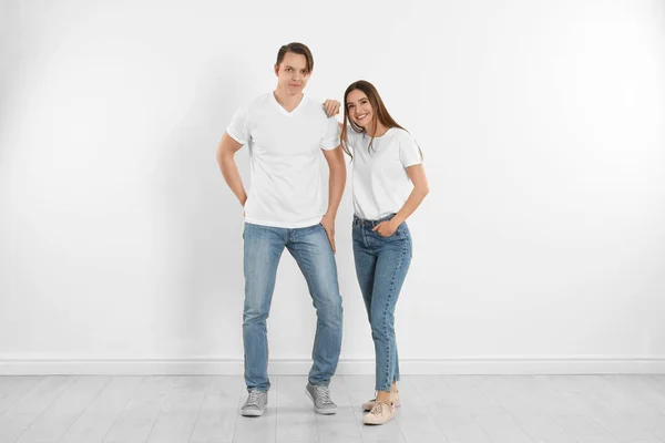 Jovem casal em jeans elegantes perto da parede branca — Fotografia de Stock