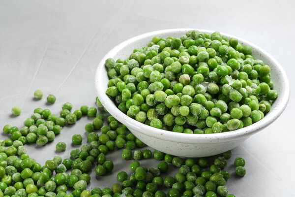 Frozen peas on light grey table, closeup. Vegetable preservation