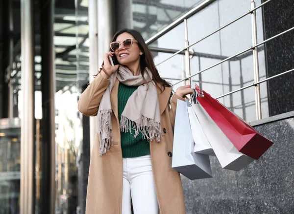 Belle jeune femme avec des sacs à provisions parler sur smartphone o — Photo