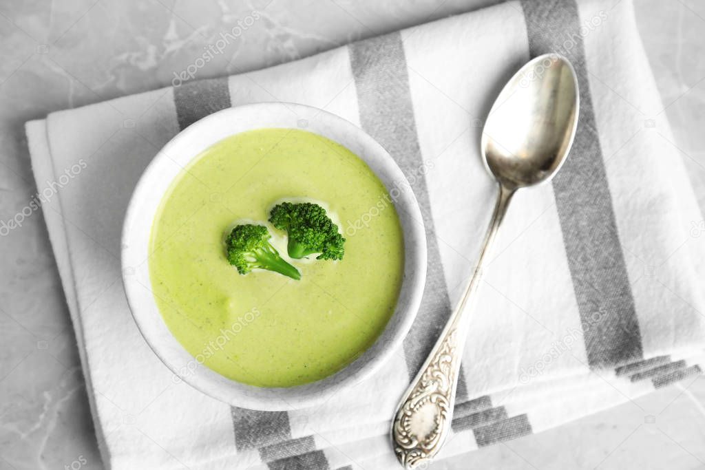 Delicious broccoli cream soup served on grey marble table, top view