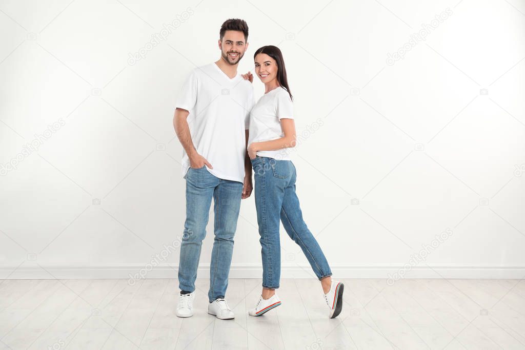 Young couple in stylish jeans near white wall