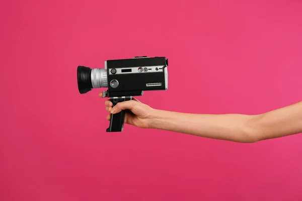 Woman with vintage video camera on crimson background, closeup o — 스톡 사진