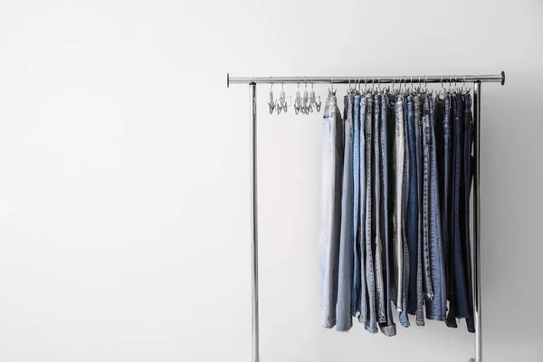 Rack with different jeans on white background. Space for text — Stock Photo, Image