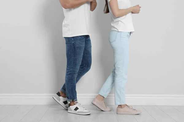 Young couple in stylish jeans near light wall, closeup — 스톡 사진