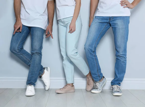 Grupo de jóvenes en jeans con estilo cerca de la pared de luz, primer plano — Foto de Stock