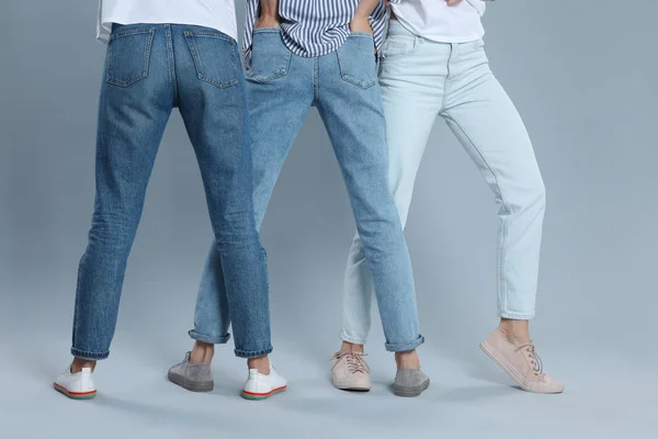 Groep jonge vrouwen in stijlvolle jeans op grijze achtergrond, closeu — Stockfoto