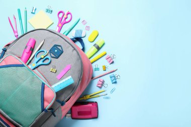 Açık mavi arka planda farklı okul kırtasiyesine sahip şık bir sırt çantası. Metin için boşluk