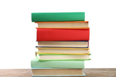 Beyaz arka plana karşı ahşap masadaki renkli kitap yığını