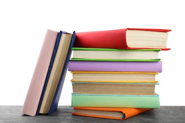 Gri taş masadaki renkli kitap yığınına karşı beyaz sırt.