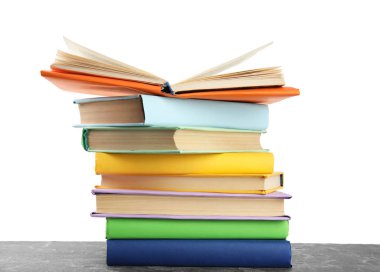 Gri taş masadaki renkli kitap yığınına karşı beyaz sırt.
