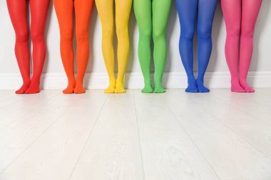 Beyaz duvarın yanında renkli tayt giyen kadınlar, yakın plan.