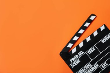 Turuncu arkaplanda el çırpma tahtası, metin için yeri olan üst görünüm. Sinema yapımı