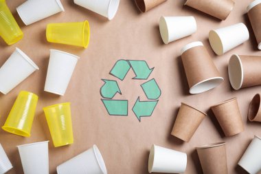 Geri dönüşüm sembolü, bej arka planda plastik ve kağıt bardaklar, düz konum