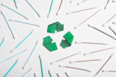 Geri dönüşüm sembolü, plastik ve ahşap pamuklu çubuklar beyaz arka planda, üst görünüm