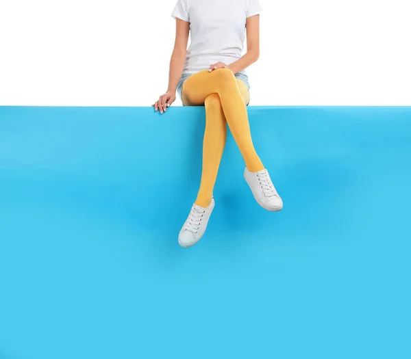 Mujer con medias amarillas y zapatos elegantes sentado en el color b — Foto de Stock
