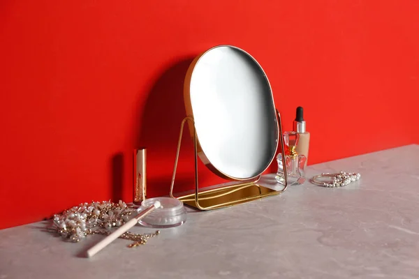 Small Mirror Makeup Products Jewelry Grey Marble Table Red Wall — ストック写真
